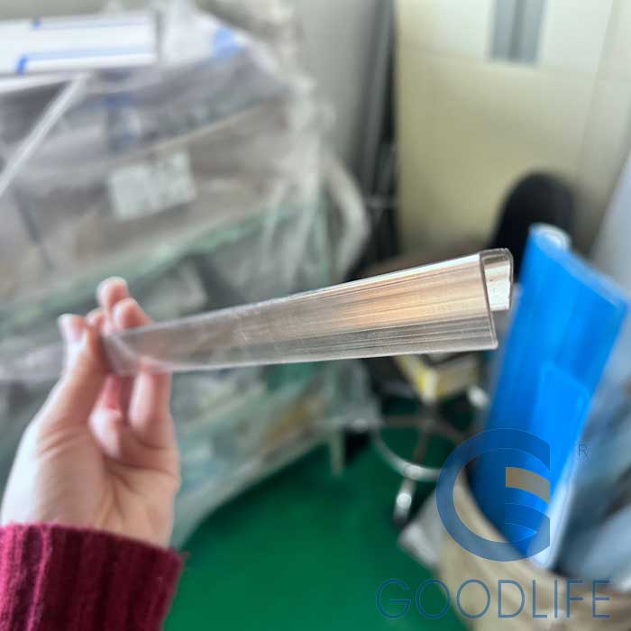 Hand hält transparenten langen Polycarbonat U-Profil-Abschlussstreifen – Flexibilität und optische Klarheit