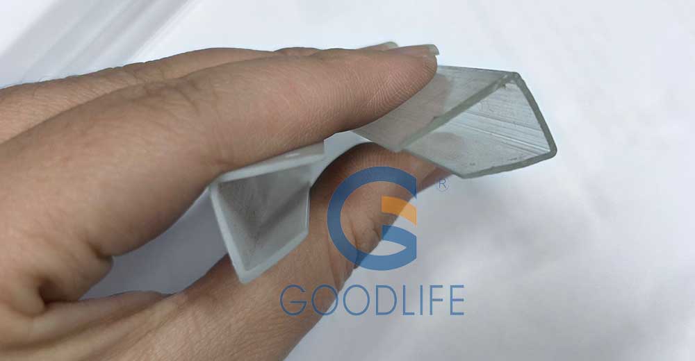 Hand hält zwei Polycarbonat U-Profil-Kantenabschlüsse – asymmetrisches Querschnittsdesign verhindert Plattenverschiebung bei Wind