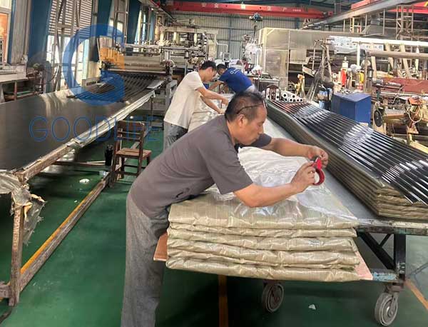 Mitarbeiter verpacken Polycarbonat-Wellplatten sicher mit strapazierfähigem Kraftpapier gegen Kratzer beim internationalen Containerversand