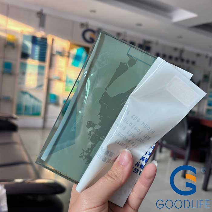 Hand holding 10mm infrared heat control solid polycarbonate sheet sample displaying light green tint from Bayer IR masterbatch in GOODLIFE factory showroom