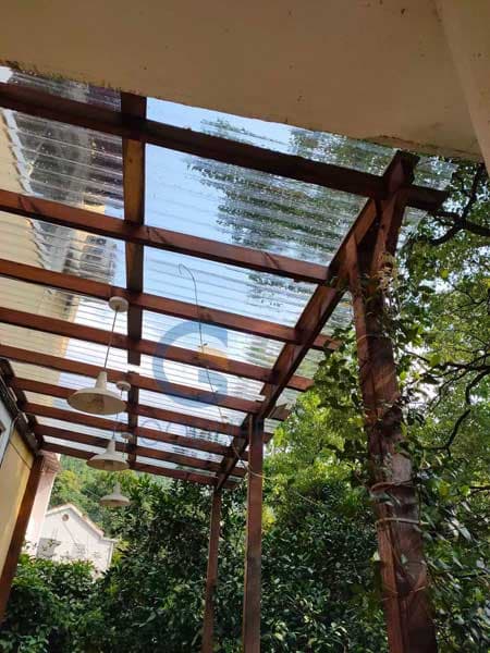 Terraza rústica en chalet residencial chileno desplegando láminas de policarbonato acanalado transparente instaladas pulcramente en estructura pergolada de madera